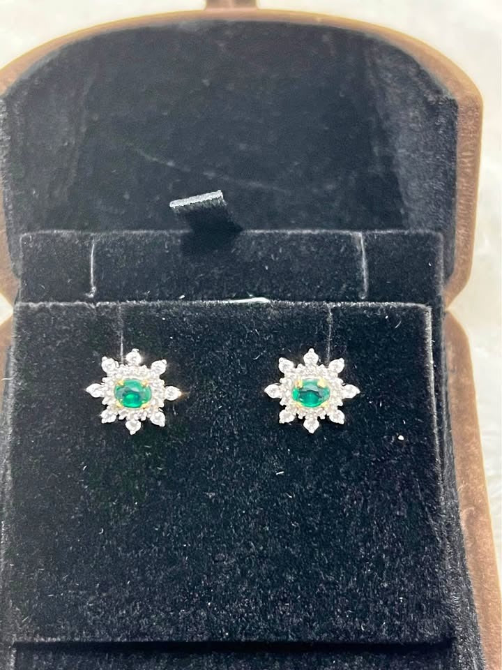 Pair of natural emerald and white topaz flower stud earrings, displayed in an open jewelry box