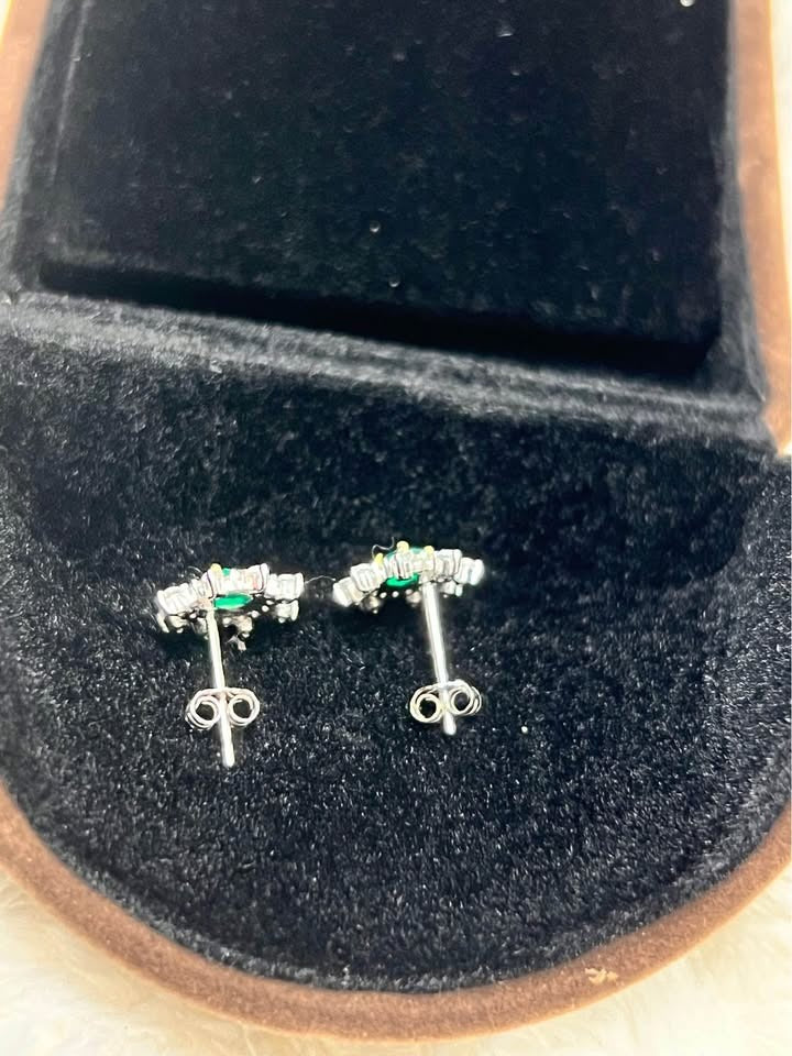 Back view of natural emerald and white topaz flower stud earrings, showing posts in box.
