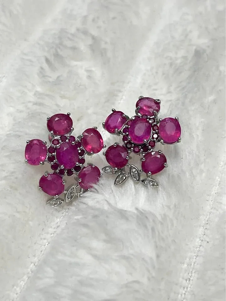 A pair of beautiful sterling silver cluster earrings with natural pink rubies on a soft, white background.
