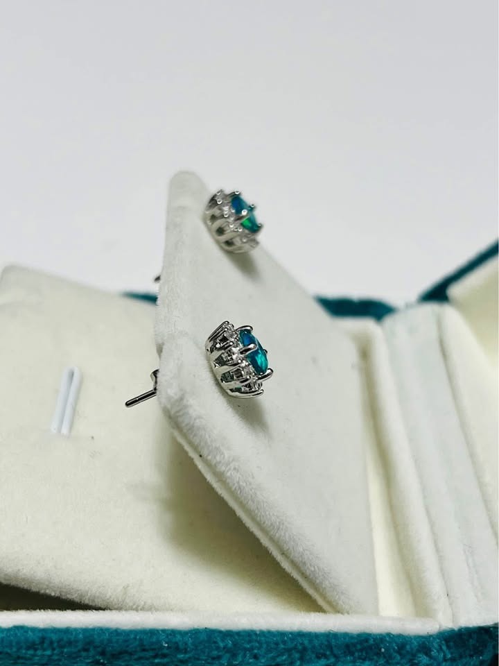 Side view of natural silver stud earrings with mesmerizing blue fire opal stones, showing the backing and setting.