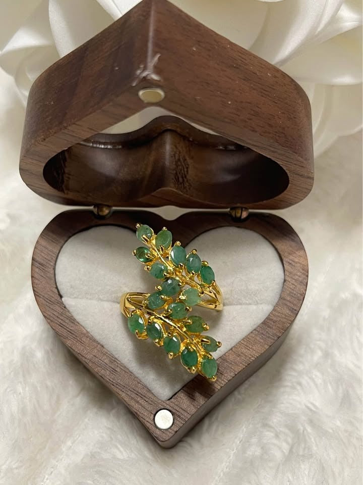 Natural sterling silver ring with unheated Colombian emeralds, shaped like a leaf, in a heart-shaped wooden box.