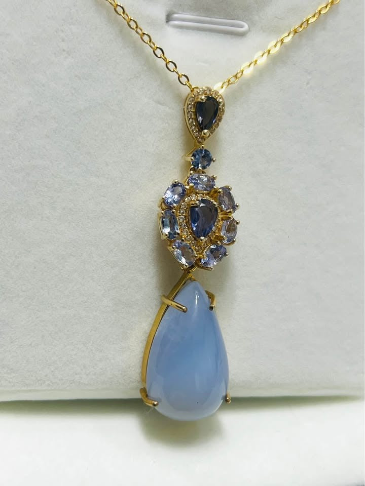 28 ct natural tanzanite and blue sapphire 2-in-1 pendant with teardrop in white display.