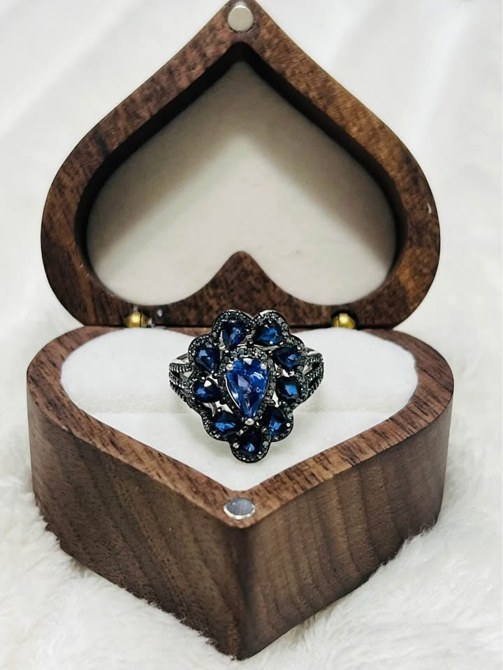 Gorgeous natural tanzanite and sapphire cocktail ring displayed in an elegant heart-shaped wooden gift box.