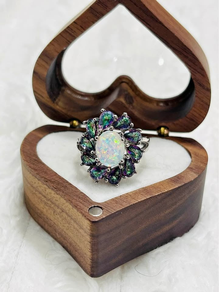  Top-down view of the stunning opal and mystic topaz ring displayed in an open wooden heart-shaped box.