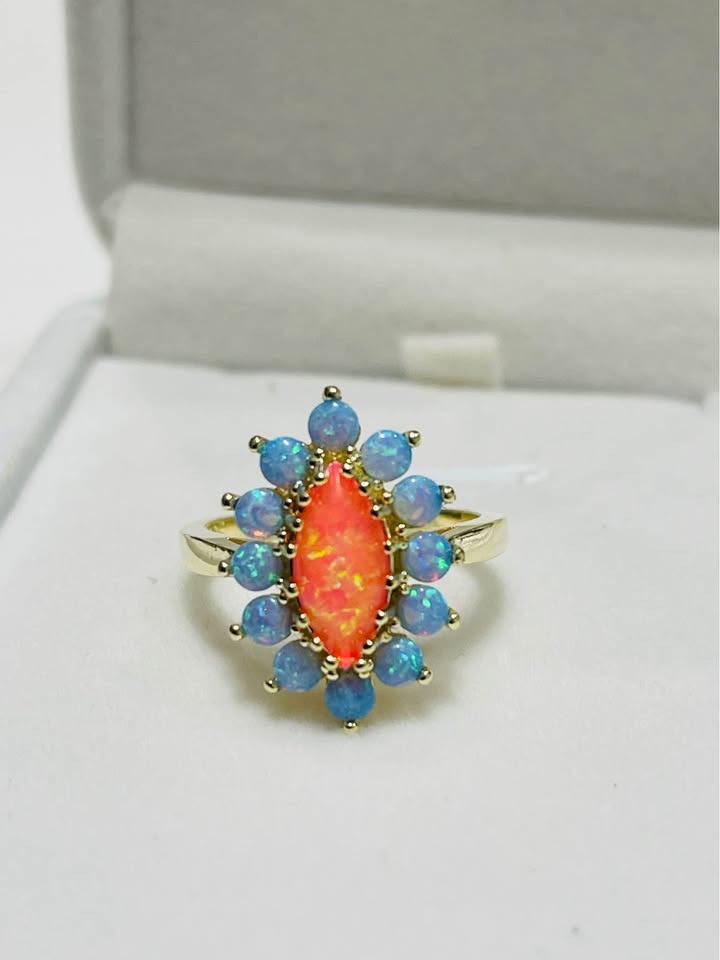 Top view of a sterling silver ring with a vibrant orange marquise opal surrounded by blue opals.