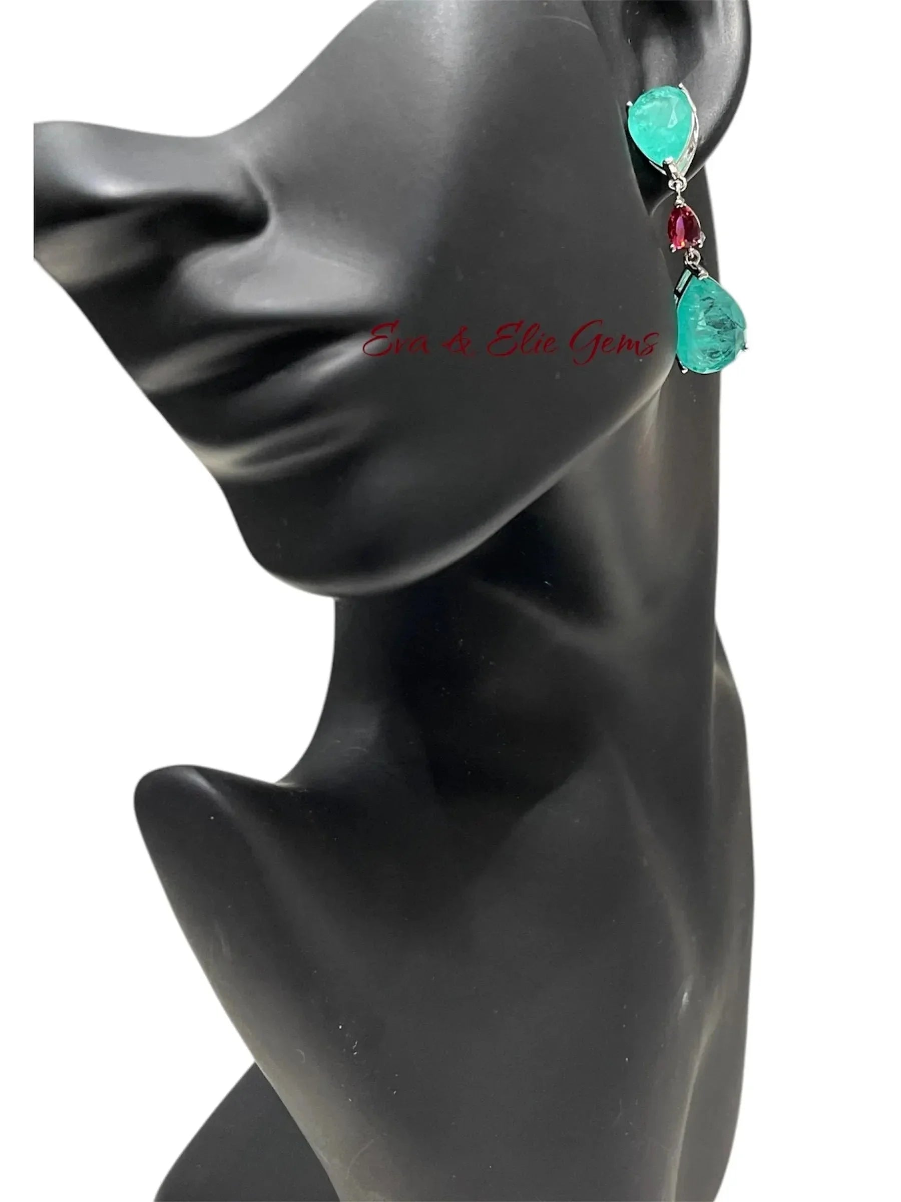 Blue-green Paraiba doublet drop earring with a red accent stone on a black mannequin ear.