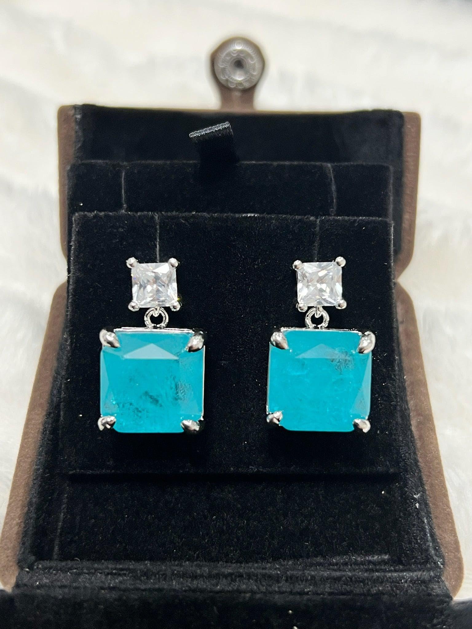 Pair of vibrant emerald-cut Paraiba tourmaline earrings with white accents, presented beautifully in a box.