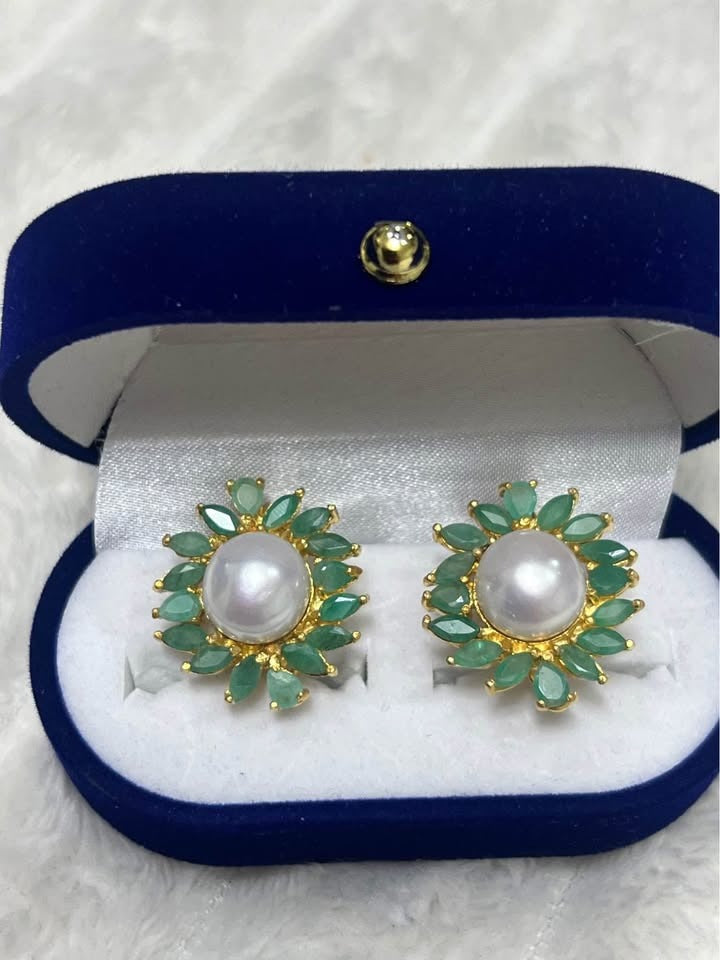 Pristine pair of natural South Sea pearl and emerald earrings, presented beautifully in a dark blue box.