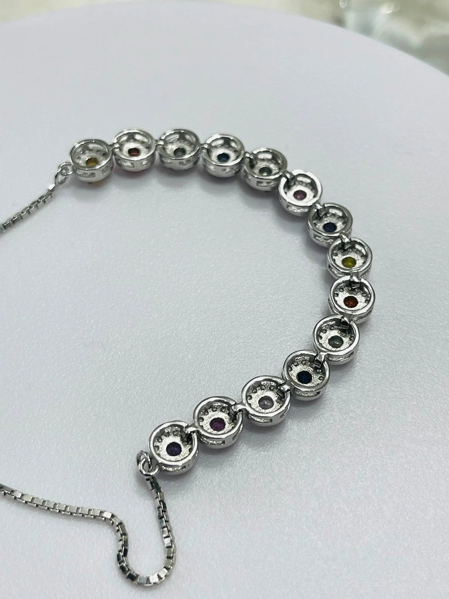 Back view of a silver bolo bracelet, revealing the settings of the round, colorful gemstones along the band.