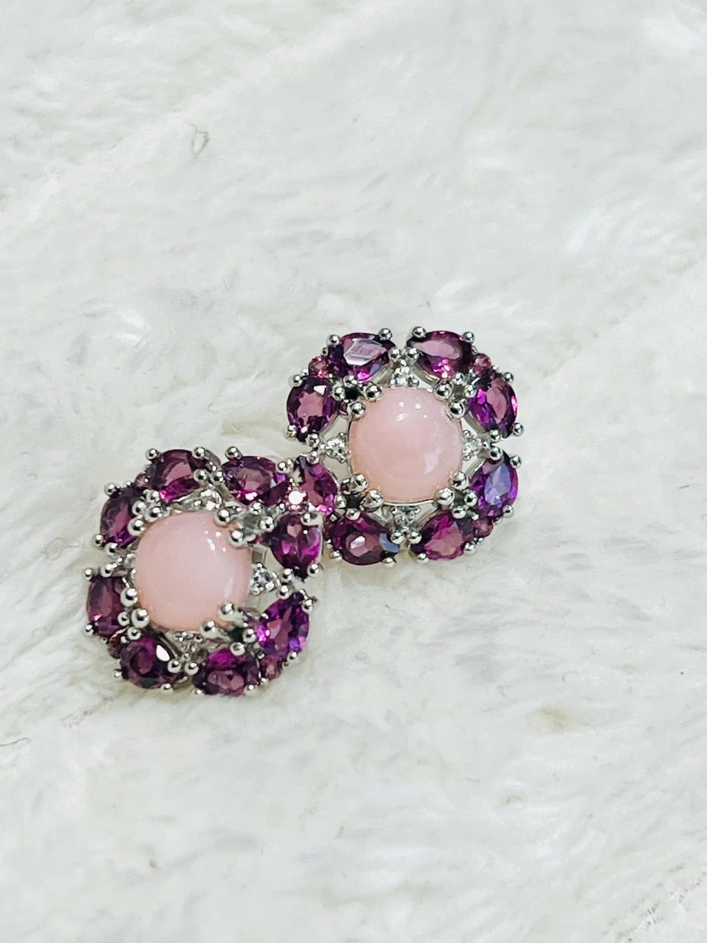 Two sterling silver earrings: round rose quartz, marquise rhodolite garnets, on soft surface.