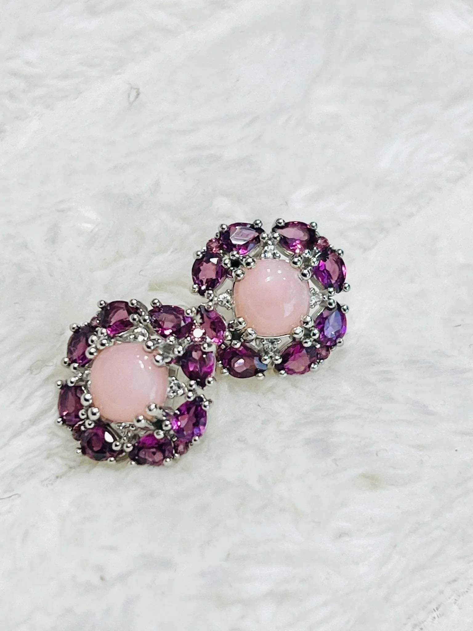 Two sterling silver earrings: round rose quartz, marquise rhodolite garnets, on soft surface.