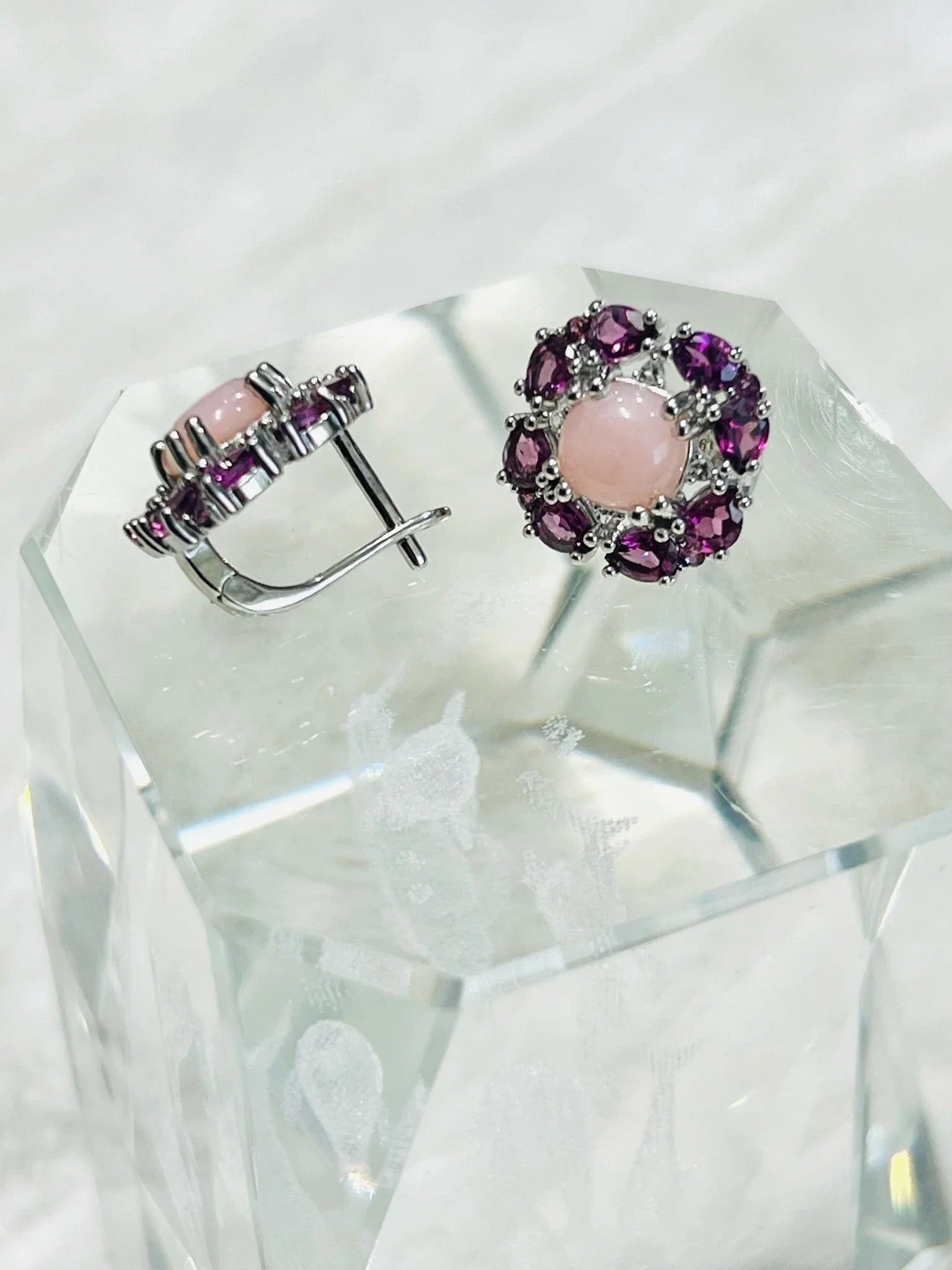 Sterling silver flower earrings with rose quartz and rhodolite garnets on a clear block, showcasing elegant design.