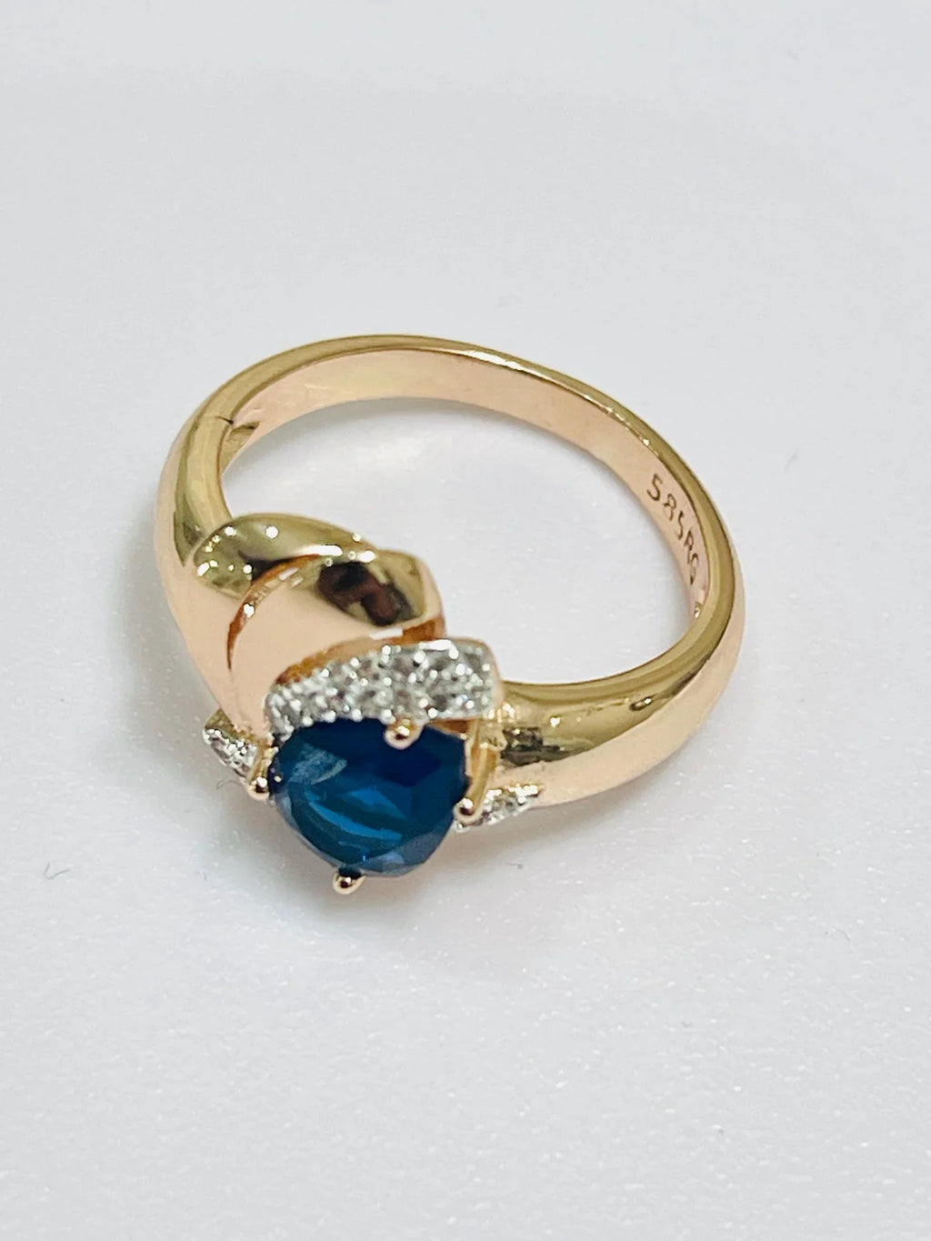 Gold ring with a blue gemstone and diamonds on a white background