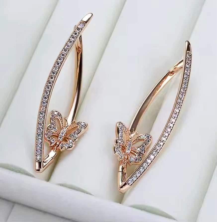 Rose gold butterfly dangle earrings with pave set diamonds, elegantly displayed on a white background.