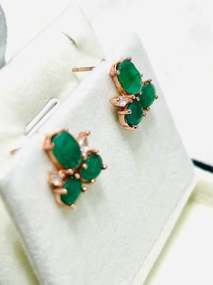 Angled view of rose gold Colombian emerald stud earrings, showcasing their intricate design.