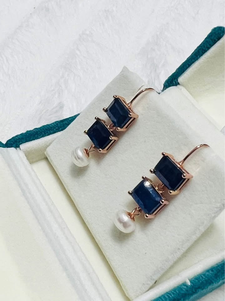 Pair of rose gold-plated silver earrings with deep blue sapphire gems and delicate white pearl drops.