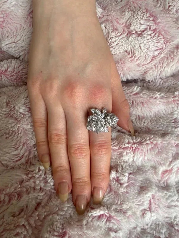 Rose-shaped gold vermeil CZ statement ring worn on a hand against a soft, textured pink background.