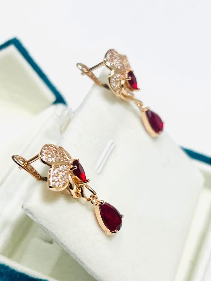 Angled display of elegant 14k 585RG stamped rose gold earrings featuring vibrant red fancy stones.