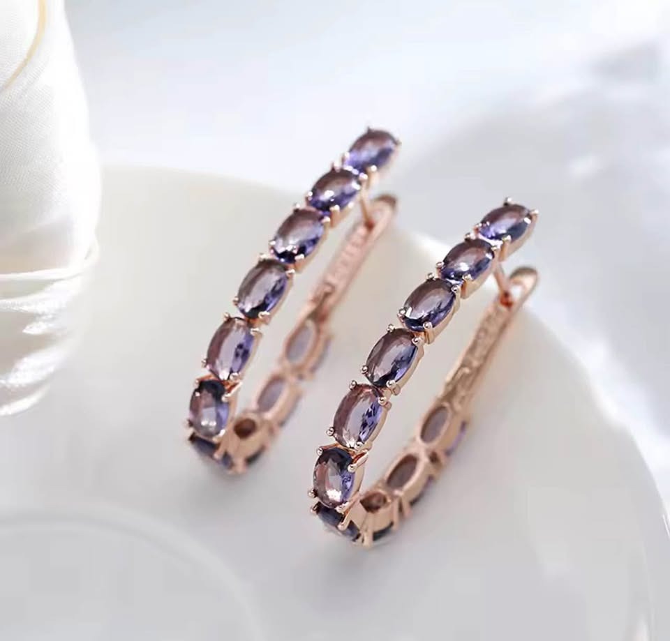 Pair of exquisite 14K rose gold hoops featuring vibrant oval amethyst gemstones on a white surface.