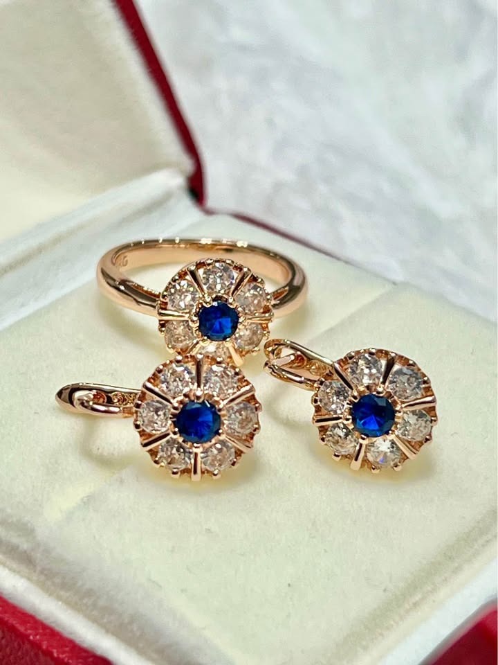 Elegant rose gold ring and earrings featuring vibrant blue sapphires surrounded by sparkling diamonds in a floral design.