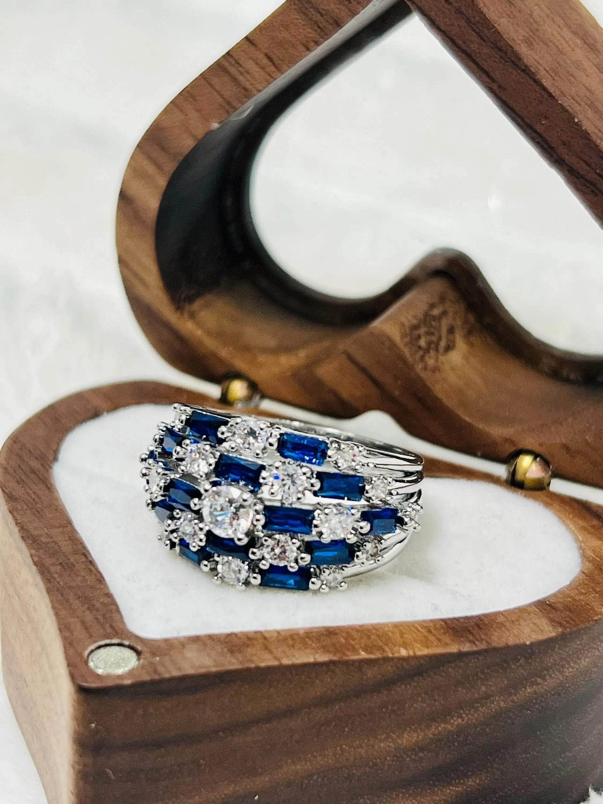 Elegant royal blue sapphire and clear stone statement ring in a silver setting, in a wooden heart box.