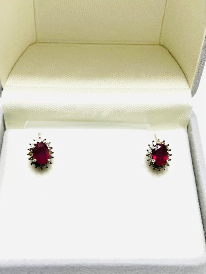 Front view of a pair of small ruby and diamond stud earrings, showcasing their vibrant color and halo design.