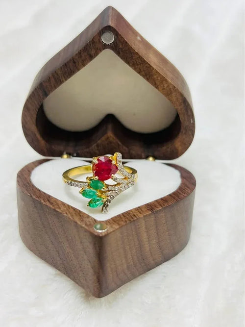  Full view of a natural ruby, emerald, and diamond floral ring in a heart-shaped wooden gift box.