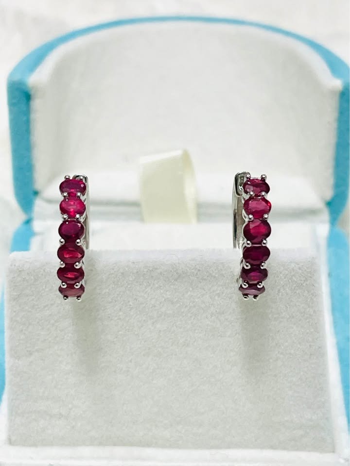  Top-down view of natural sterling silver ruby huggie hoop earrings in an open jewelry gift box.
