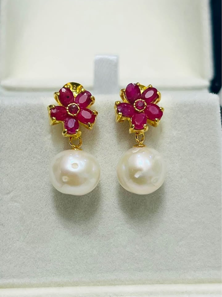Beautiful natural pink ruby flower top and genuine South Sea pearl dangle earrings on a white display.