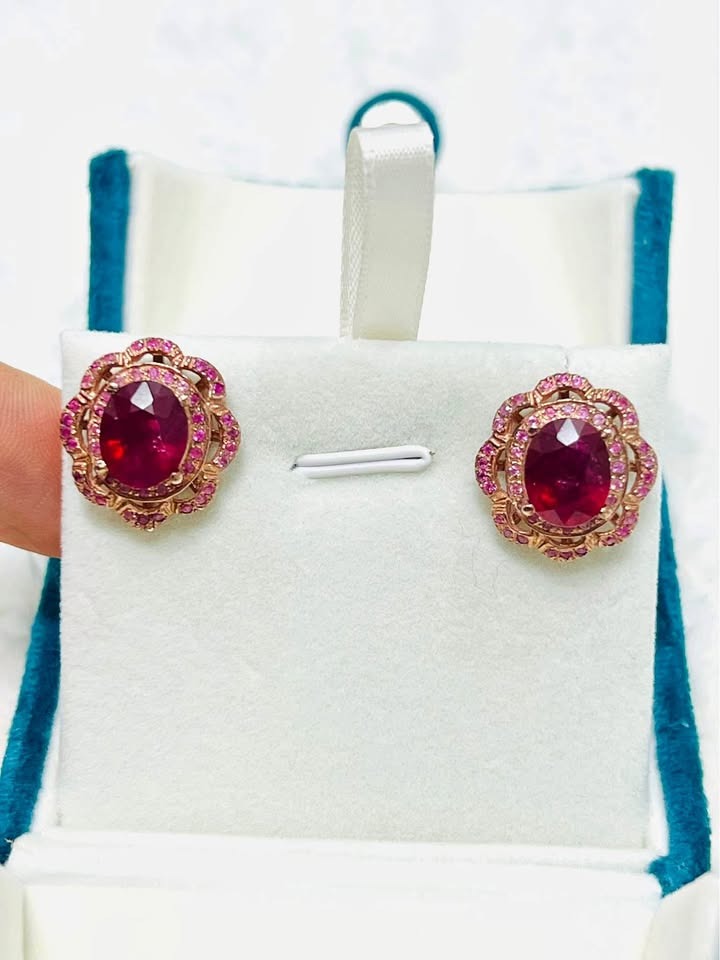 Elegant ruby and pink sapphire stud earrings presented beautifully in a teal display box.