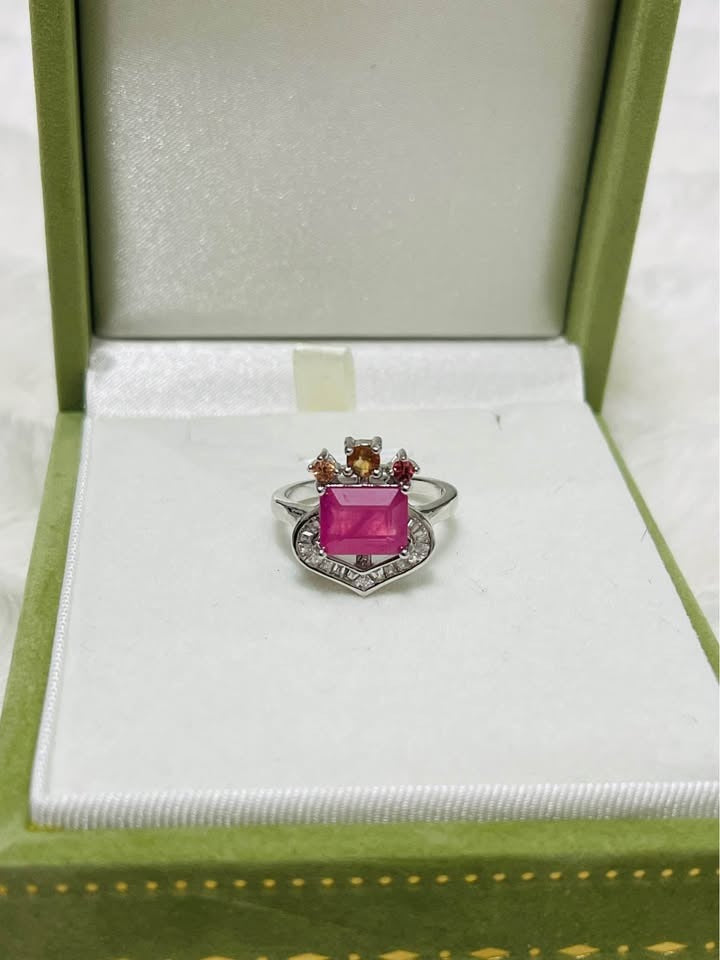 Natural 3 carat ruby and colored sapphire ring displayed elegantly in an open green jewelry box.