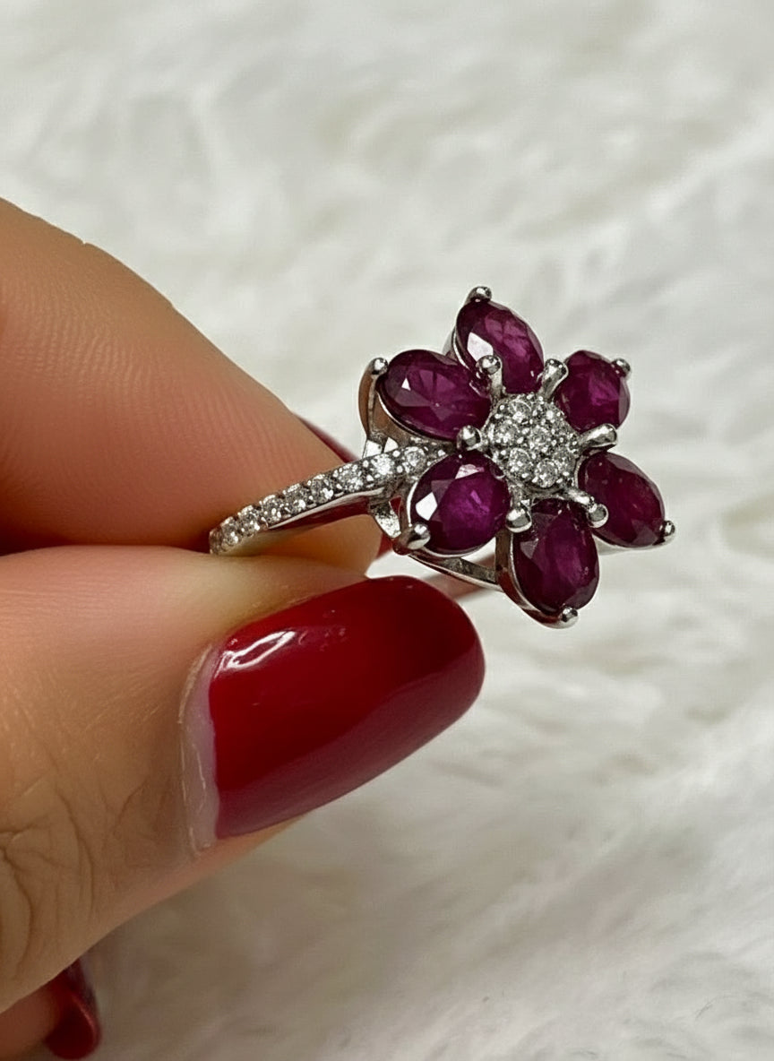 Angled view of a stunning natural ruby and white stone flower ring.