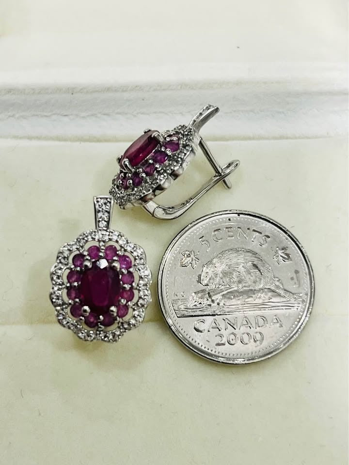 Rhodium-plated sterling silver ruby halo earrings next to a Canadian 5-cent coin for size comparison, showcasing details.