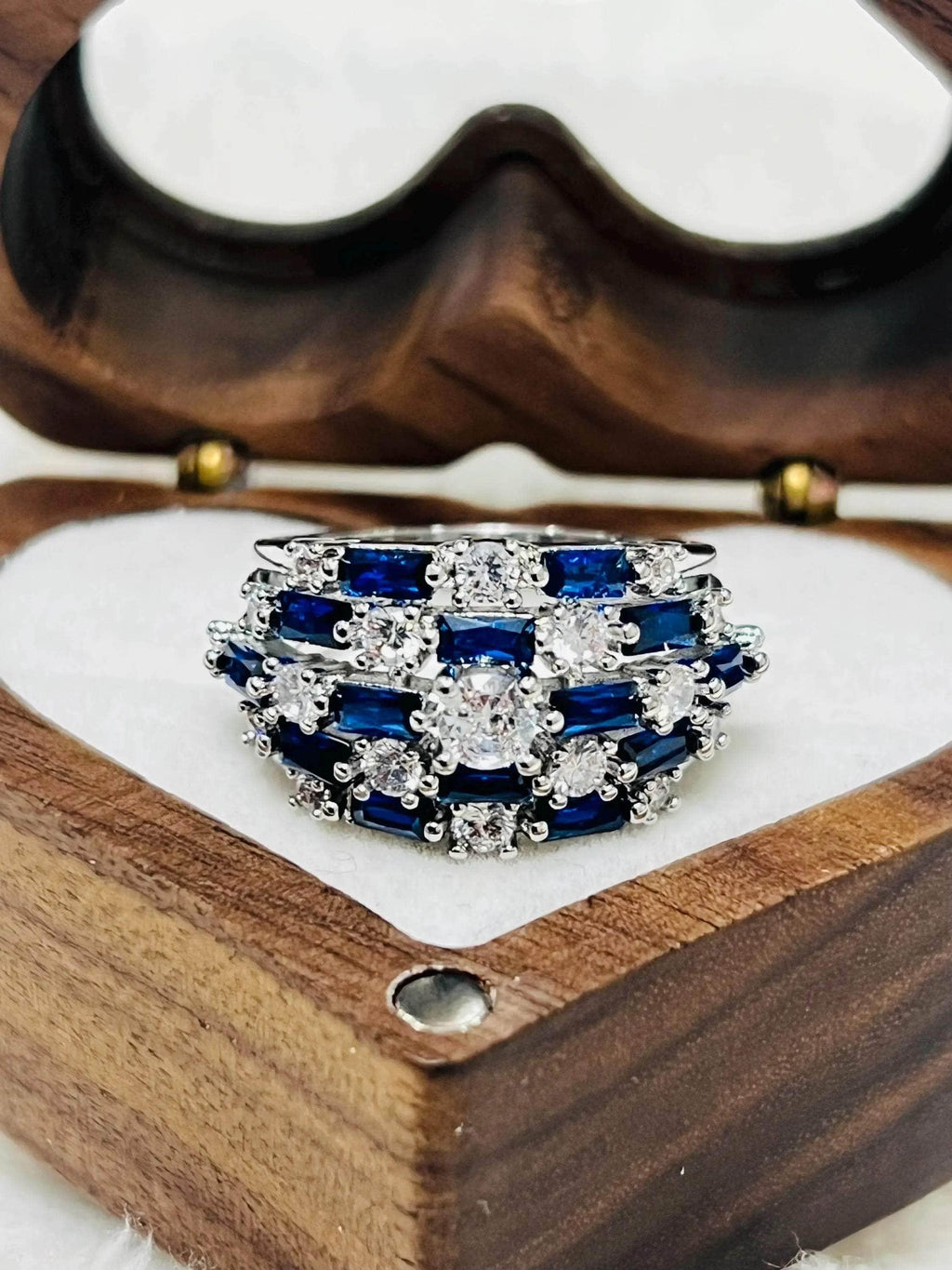 Close-up of a sapphire and diamond statement ring, nestled in a charming heart-shaped wooden jewelry box.