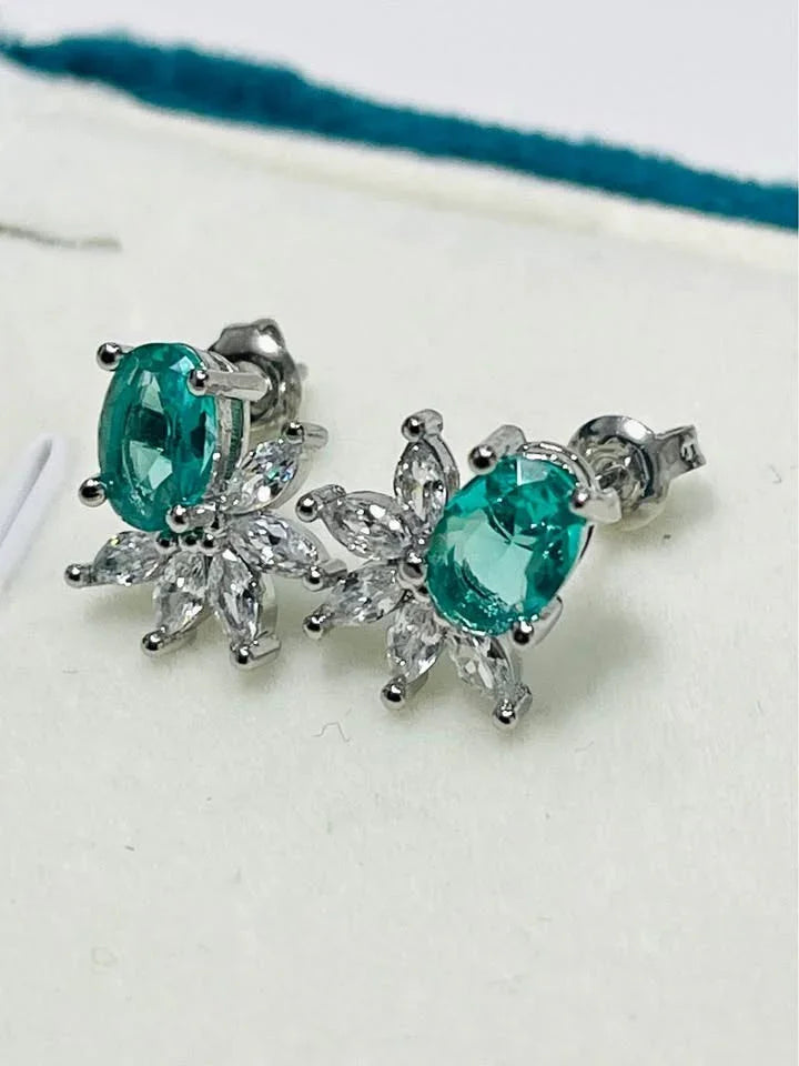 A close-up side view of the sterling silver earrings, highlighting the brilliant green paraiba tourmaline and sparkling details.