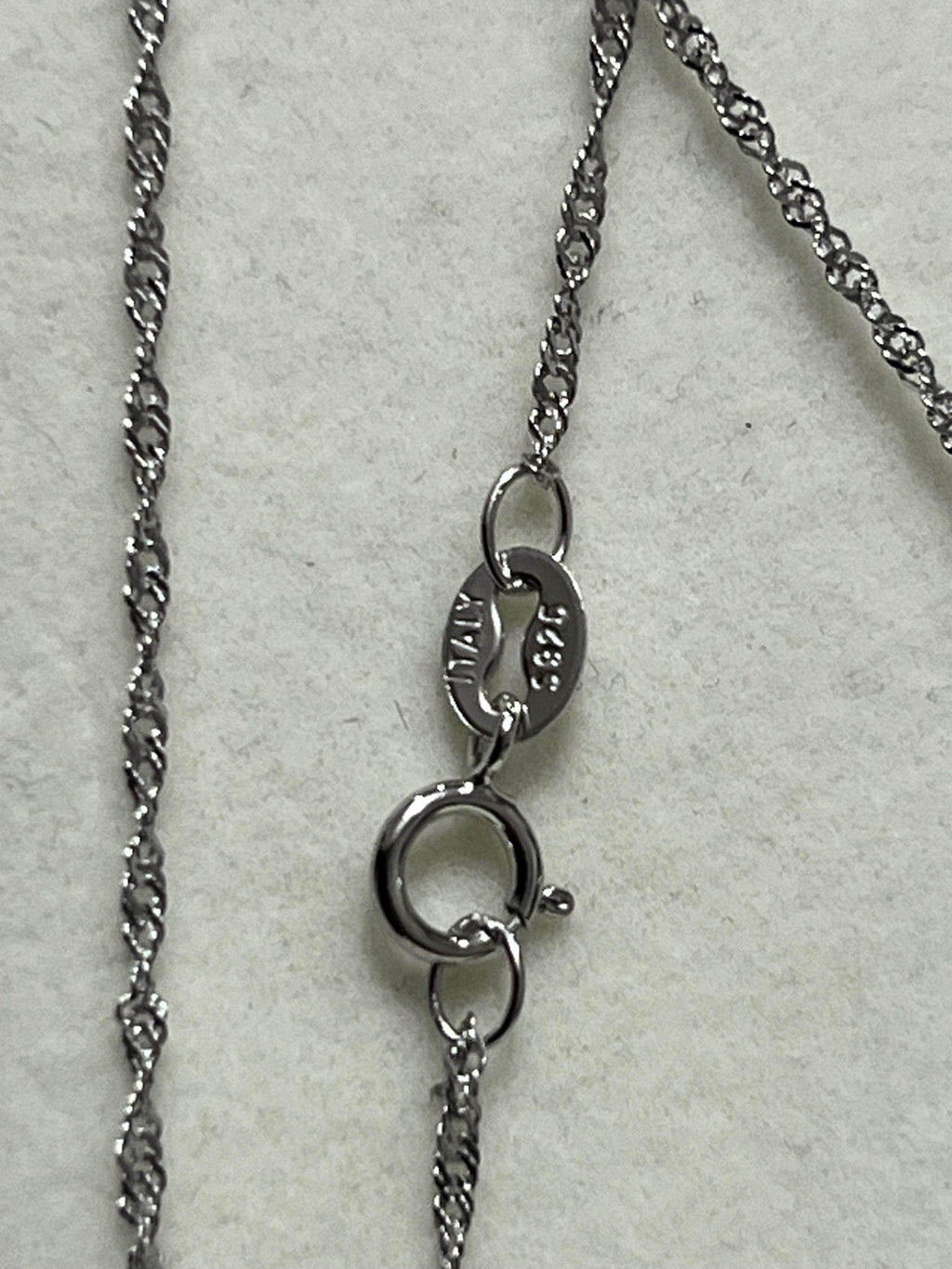  Close-up of a sterling silver (925) chain with an "ITALY" stamp on the clasp, indicating origin.