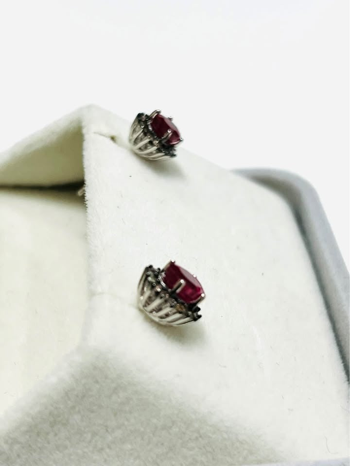  Side view of elegant small stud earrings featuring an oval ruby centerpiece surrounded by sparkling diamonds.