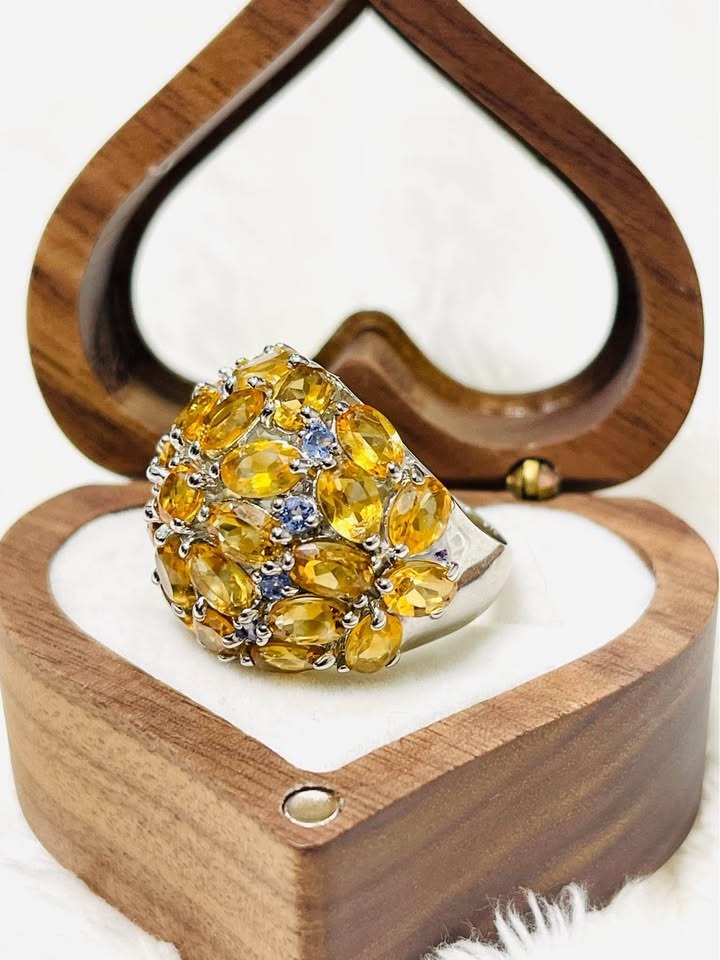 Side angle of a sterling silver statement ring adorned with numerous sparkling citrine and blue tanzanite gems