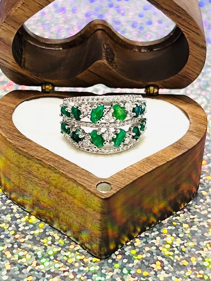 Beautiful sterling silver ring featuring natural emeralds and sparkling accents, displayed in a wooden box.