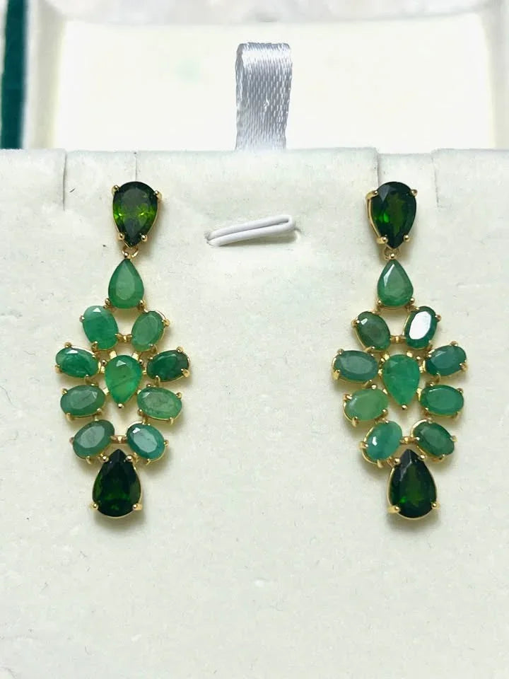 A close display of stunning sterling silver chandelier earrings with beautiful, multifaceted natural emeralds.