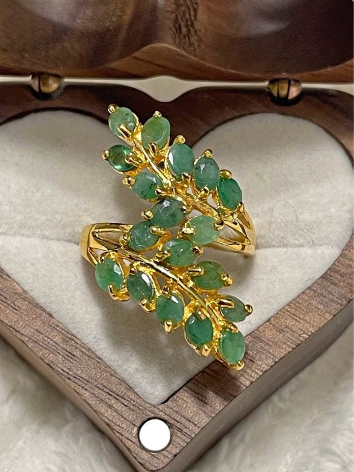 A close-up shot of a sterling silver ring with a double-leaf design set with unheated Colombian emeralds.