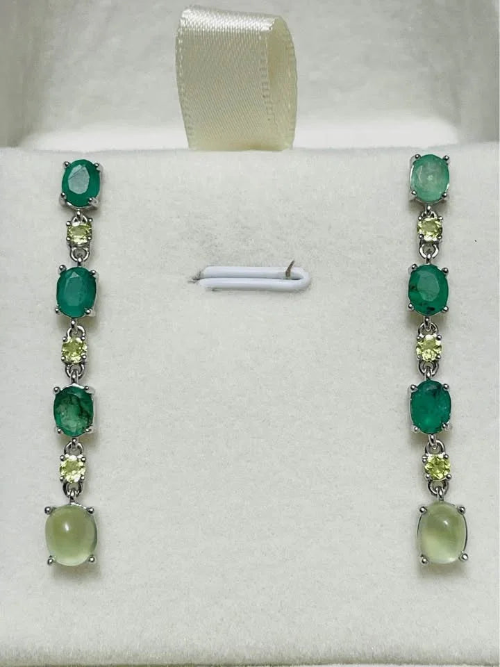 Sterling silver emerald, peridot, and prehnite dangle earrings on a white jewelry display.