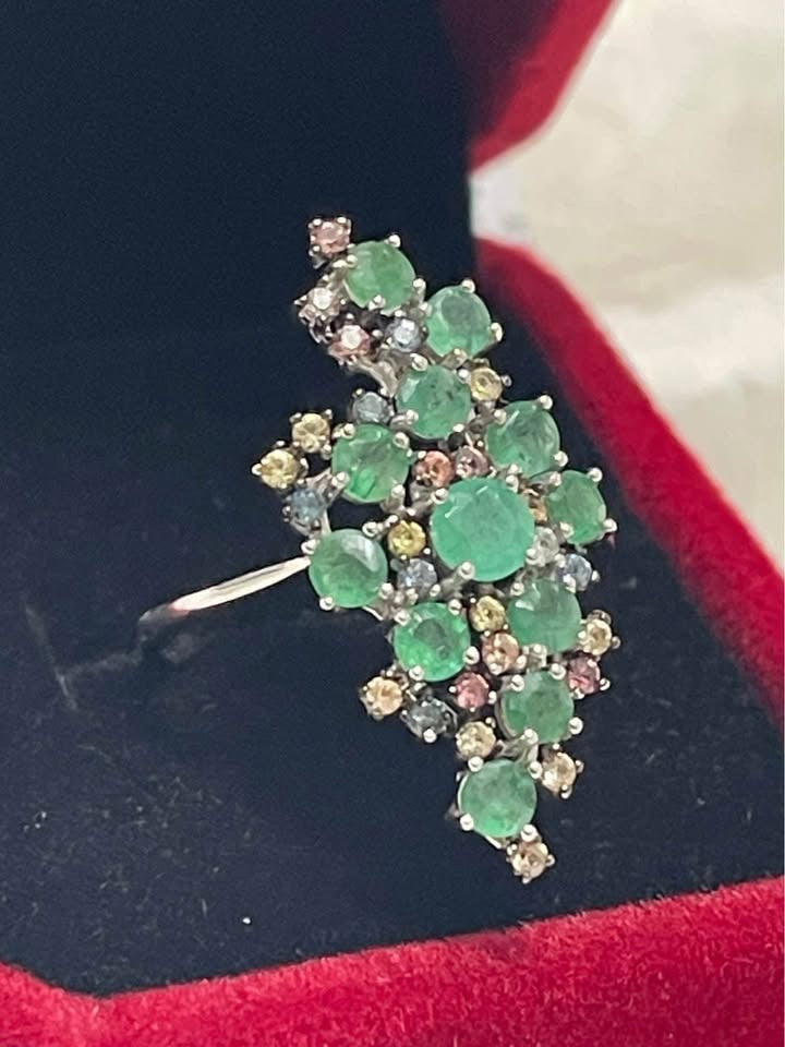  Side profile of a sterling silver earring, showcasing the three-dimensional, clustered design of emeralds and sapphires.