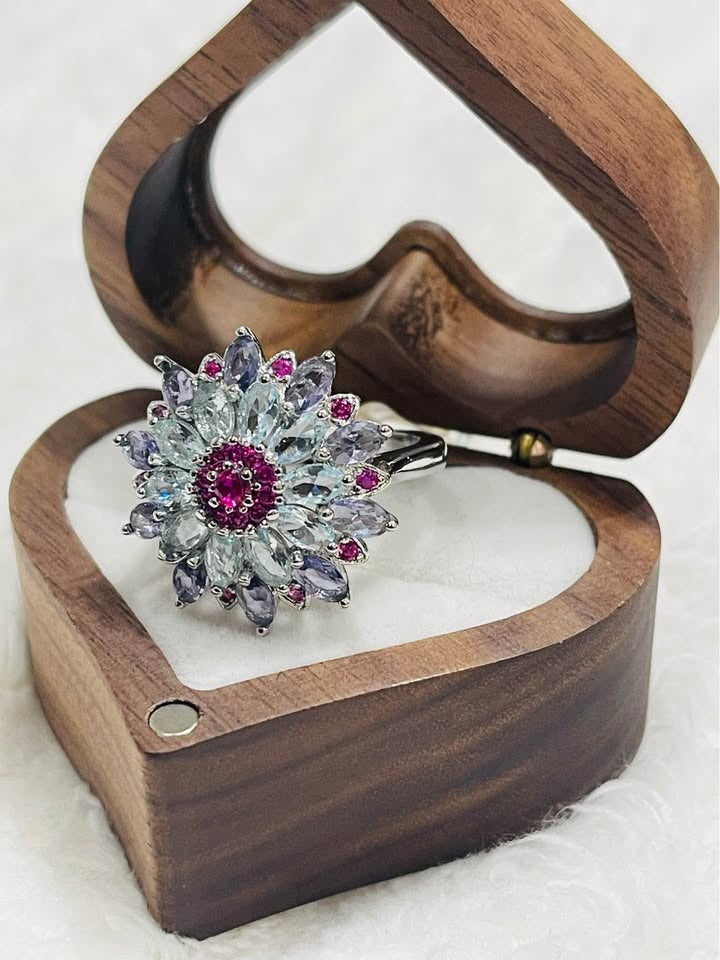 A breathtaking sterling silver ring featuring a floral design with mixed gemstones, presented in an open wooden box.