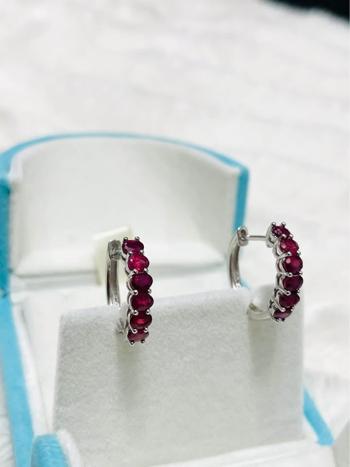 Pair of natural ruby sterling silver huggie hoop earrings displayed in a light blue jewelry box.