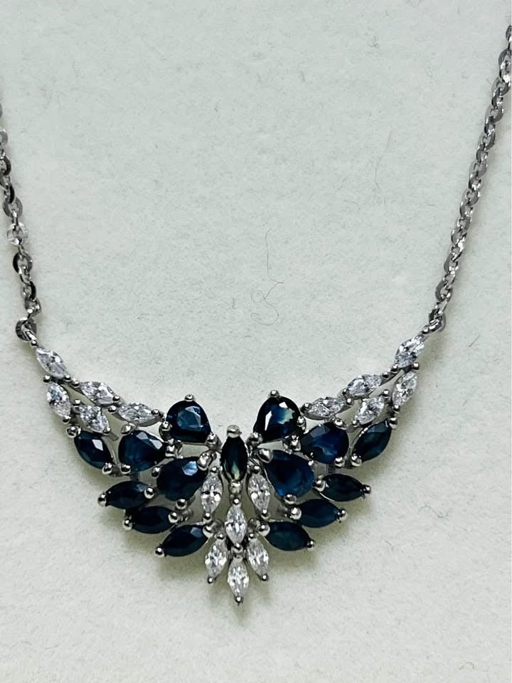 Close-up of a sterling silver pendant necklace, showcasing a beautiful floral cluster of natural blue sapphires.