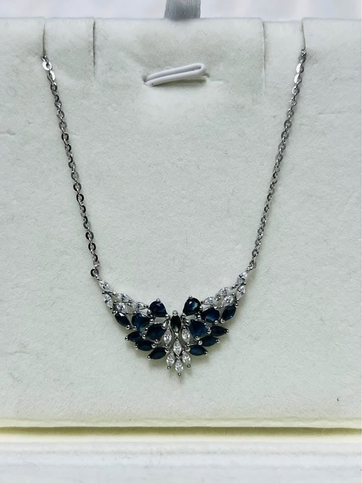 Sterling silver pendant necklace with a brilliant sapphire cluster, elegantly presented on a gray jewelry display.