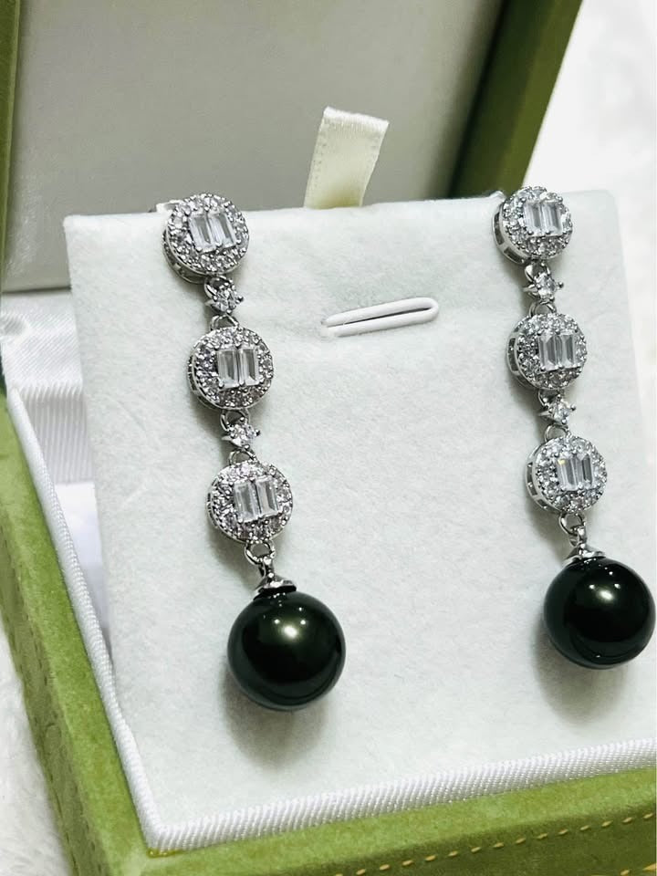 Close-up of sterling silver drop earrings with iridescent peacock Tahitian pearls and sparkling cubic zirconia