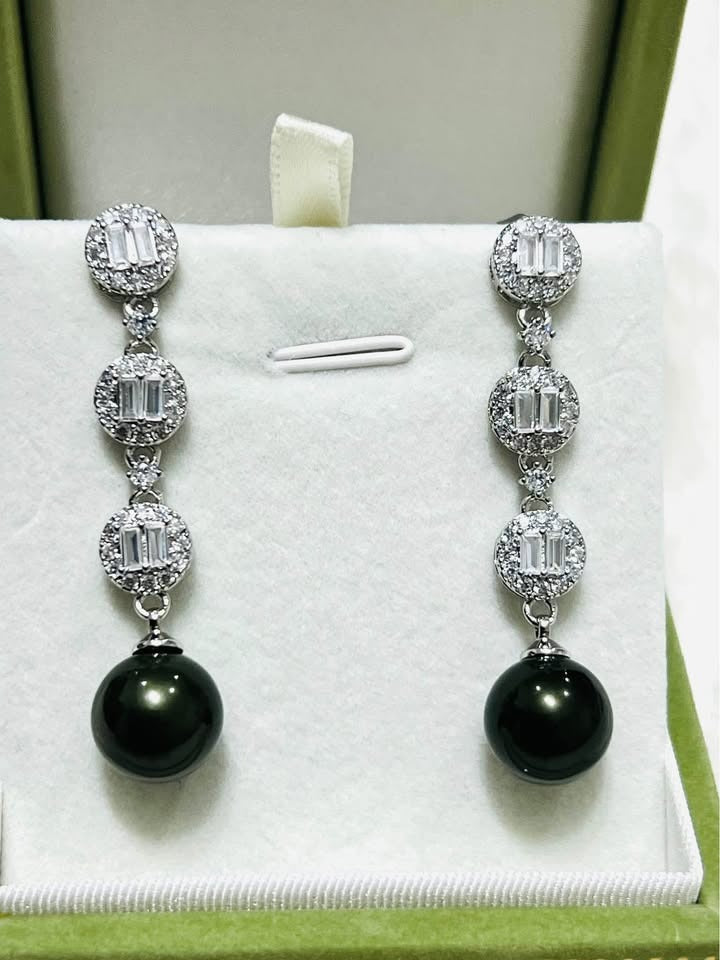 A pair of sterling silver dangle earrings with dark, iridescent Tahitian pearls and sparkling baguette-cut cubic zirconia.