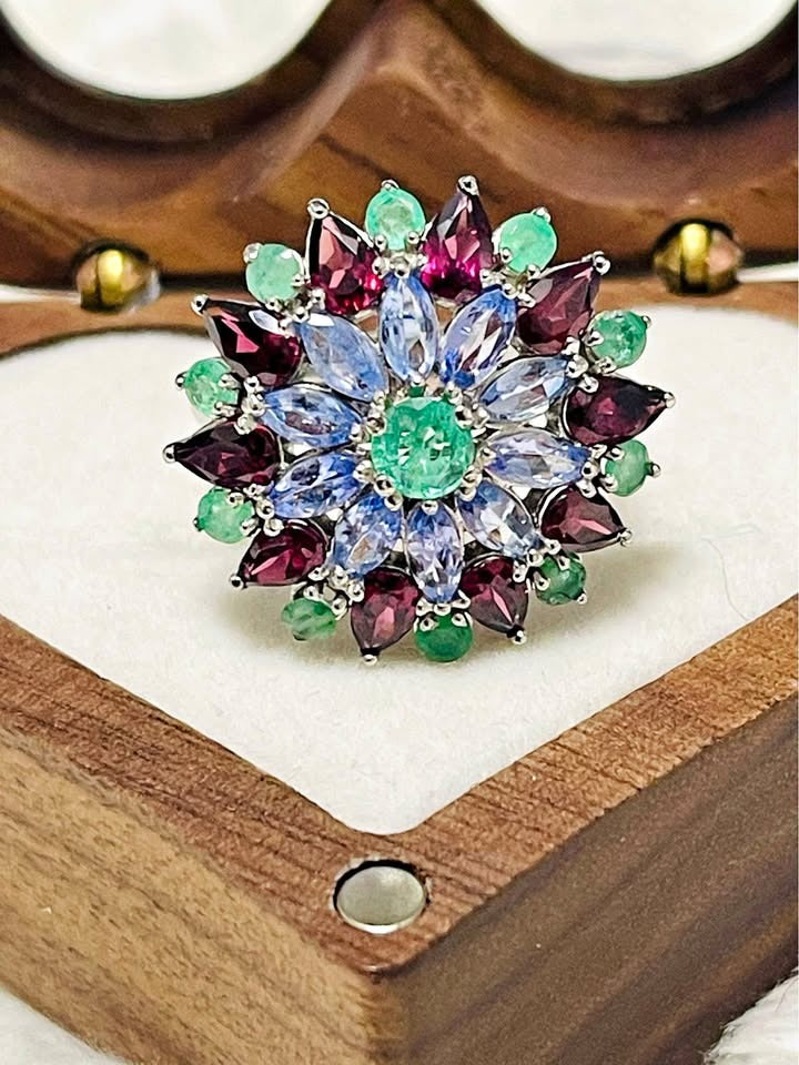  Sterling silver statement ring with a large floral design. The gemstones include tanzanite, emerald, and rhodolite garnet.